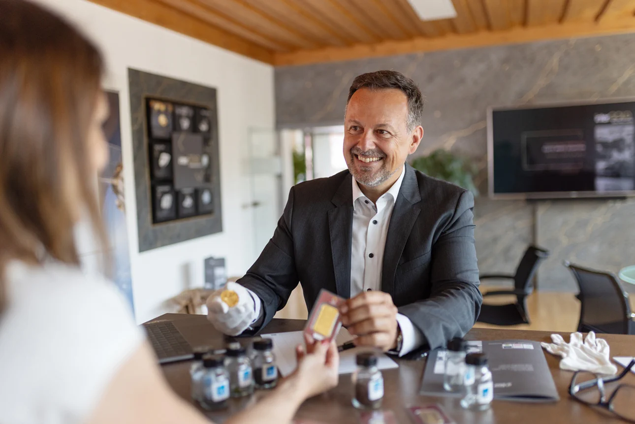 Erika Müller und Peter Hofer halten einen kleinen Goldbarren.