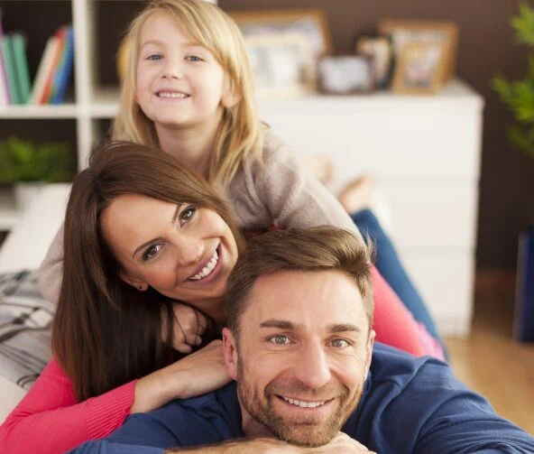 Lächelnde Familie auf dem Sofa liegend.